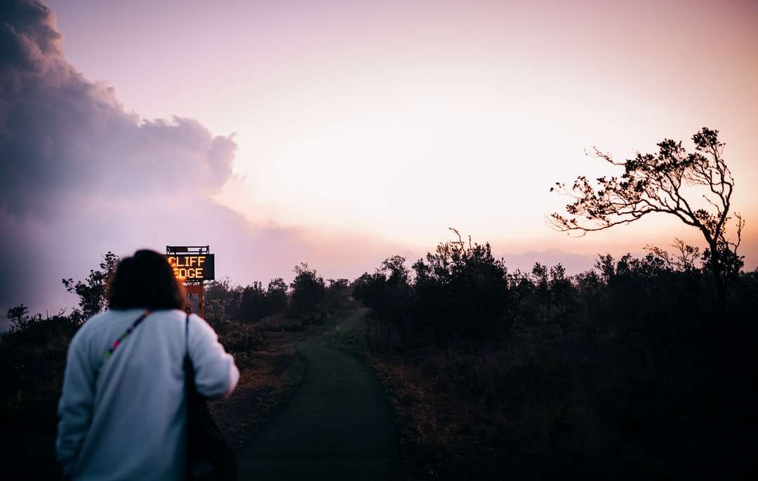 mężczyzna w białej koszuli stojący na drodze podczas zachodu słońca puzzle online