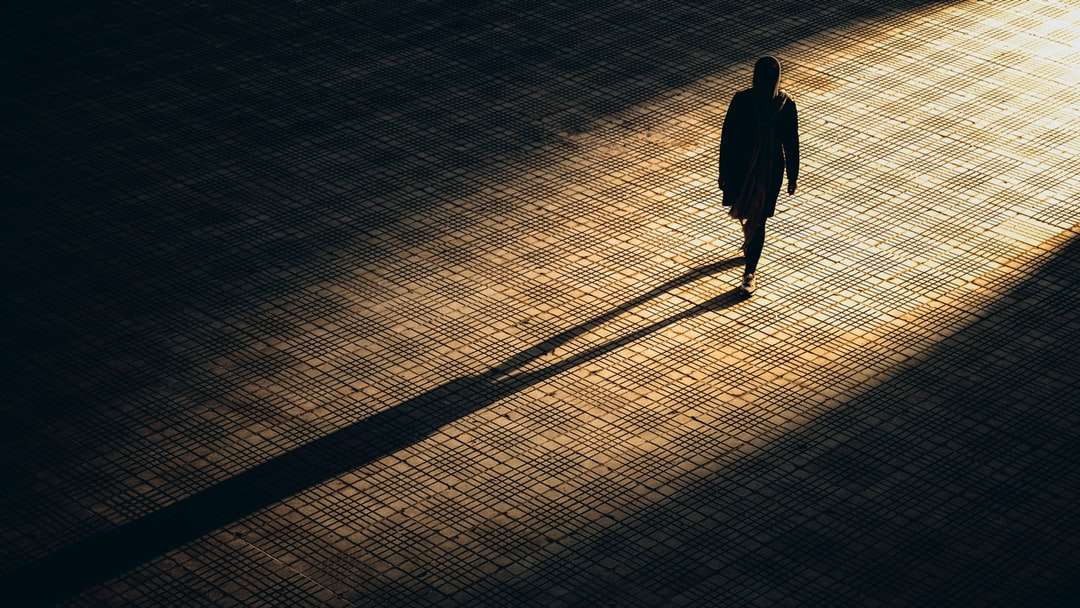 mężczyzna w czarnej kurtce chodzenie po brązowej podłodze z cegły puzzle online