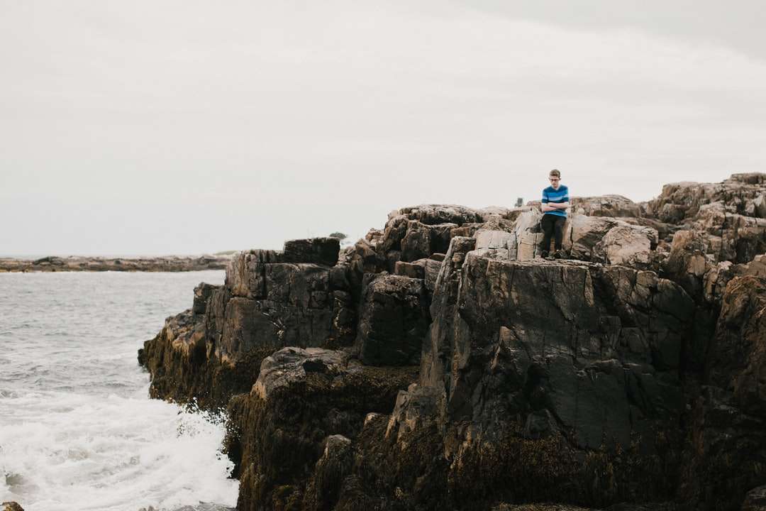 mężczyzna w niebieskiej koszuli siedzi na formacji skalnej w pobliżu ciała puzzle online
