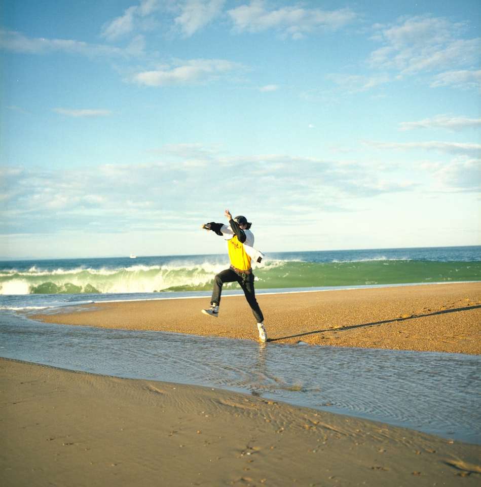 kobieta w czarnej kurtce i żółtej spódnicy stojącej nad brzegiem morza puzzle online