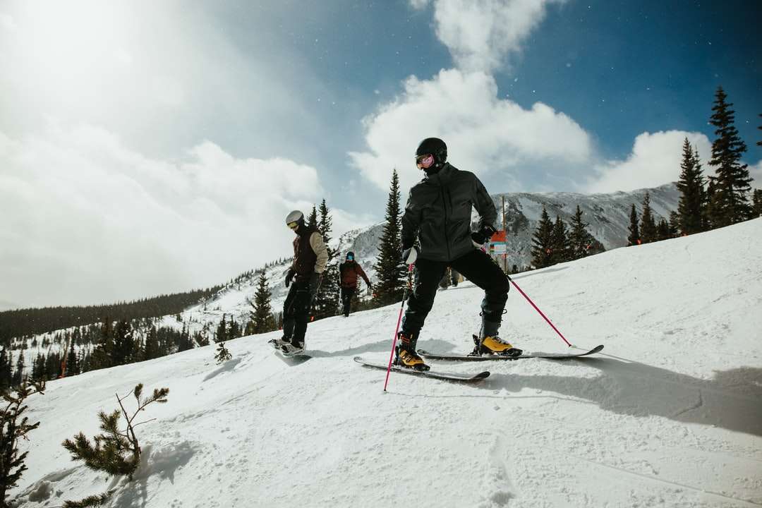 mężczyzna w czarnej kurtce i niebieskich spodniach jadący na nartach puzzle online
