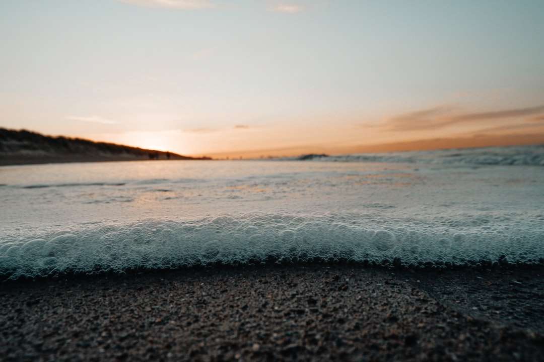 fale oceanu rozbijające się o brzeg podczas zachodu słońca puzzle online