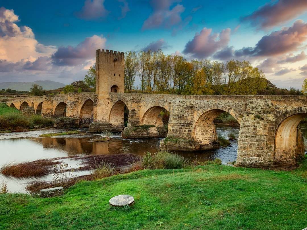 brązowy betonowy most nad rzeką pod błękitnym niebem puzzle online