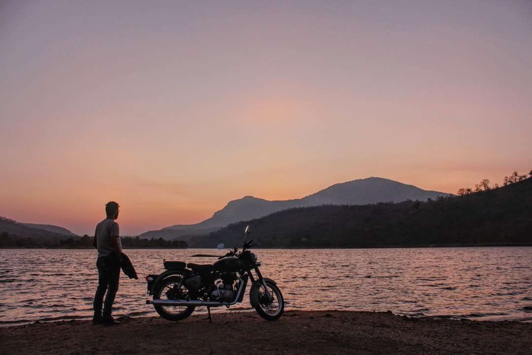 mężczyzna i kobieta stojąca obok motocykla w pobliżu zbiornika wodnego puzzle online