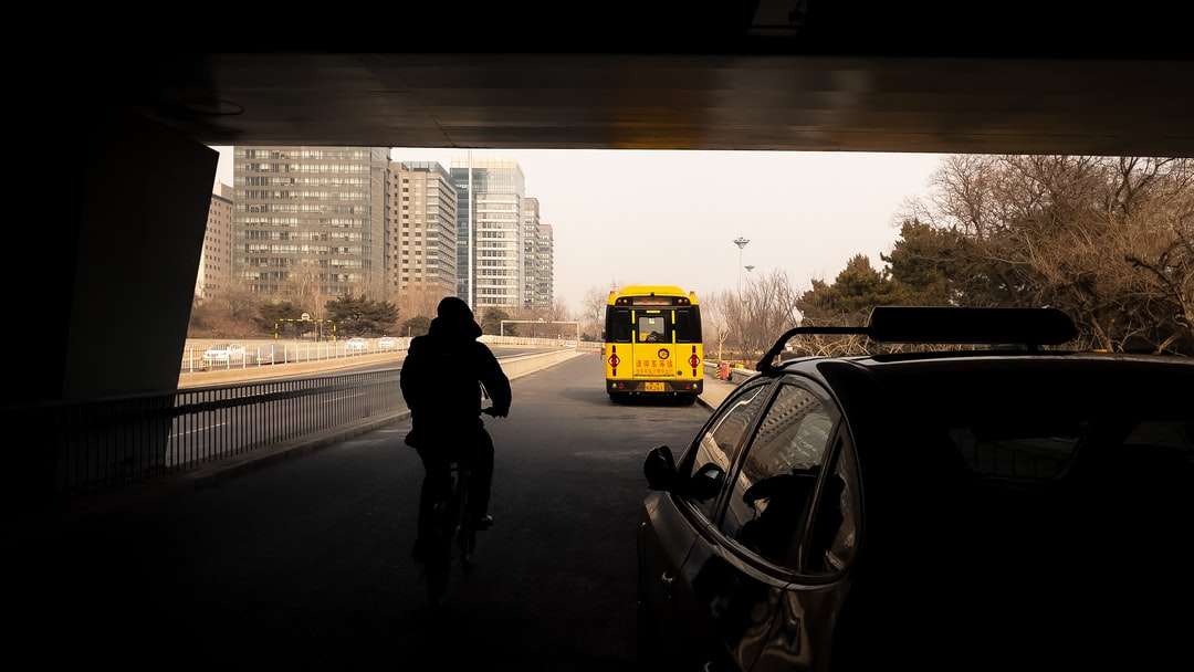 mężczyzna w czarnej kurtce stojący obok żółtego autobusu szkolnego puzzle online