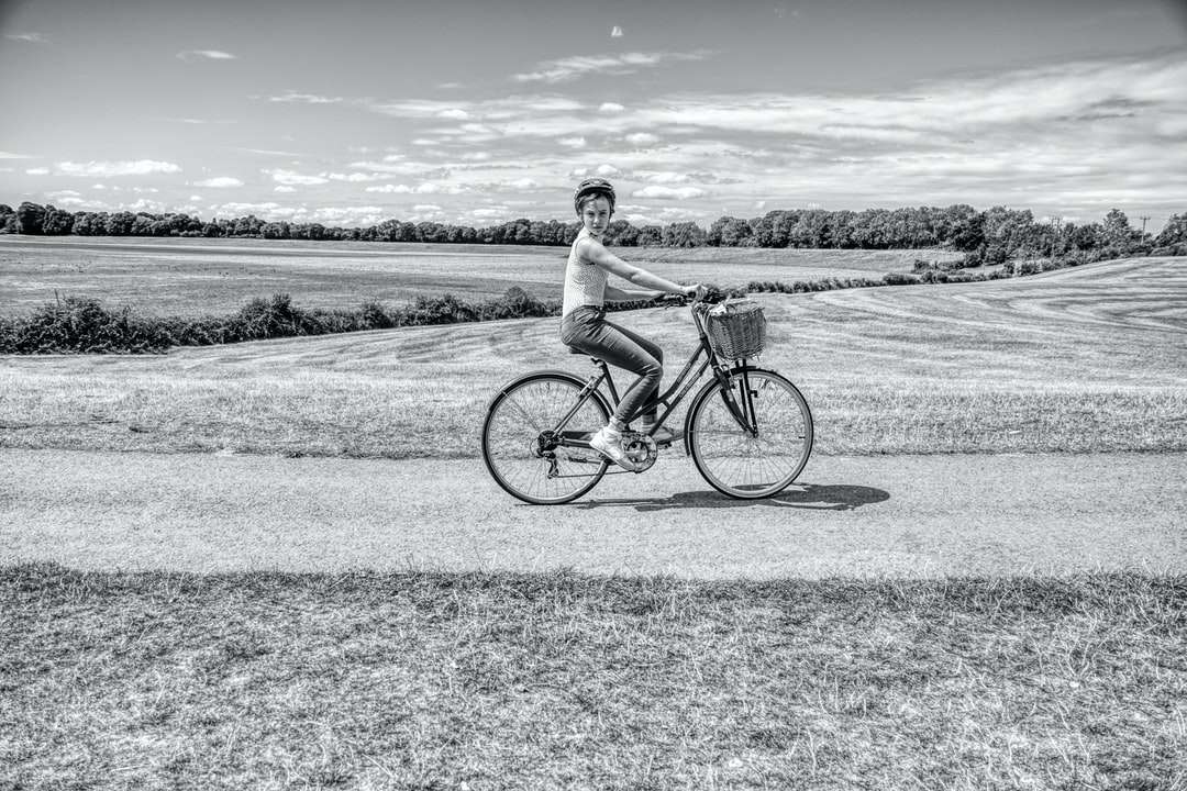 zdjęcie w skali szarości człowieka jadącego na rowerze po drodze puzzle online