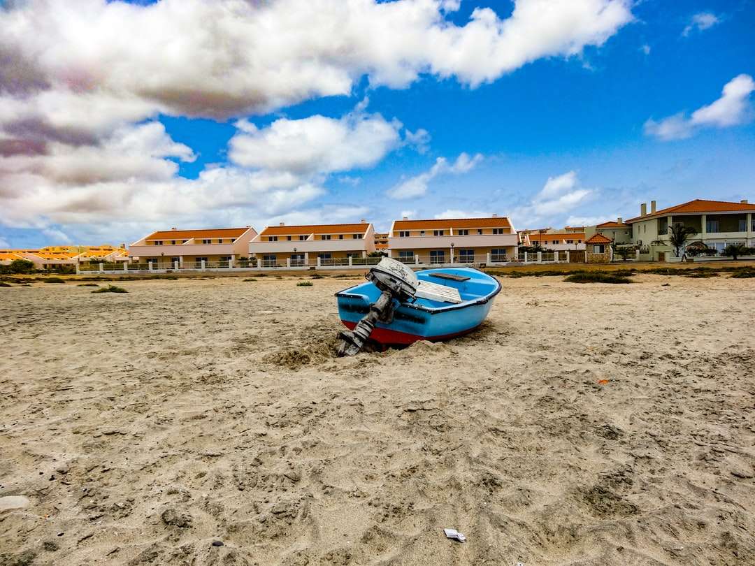 niebiesko-biała łódź na brązowym piasku pod błękitnym niebem puzzle online