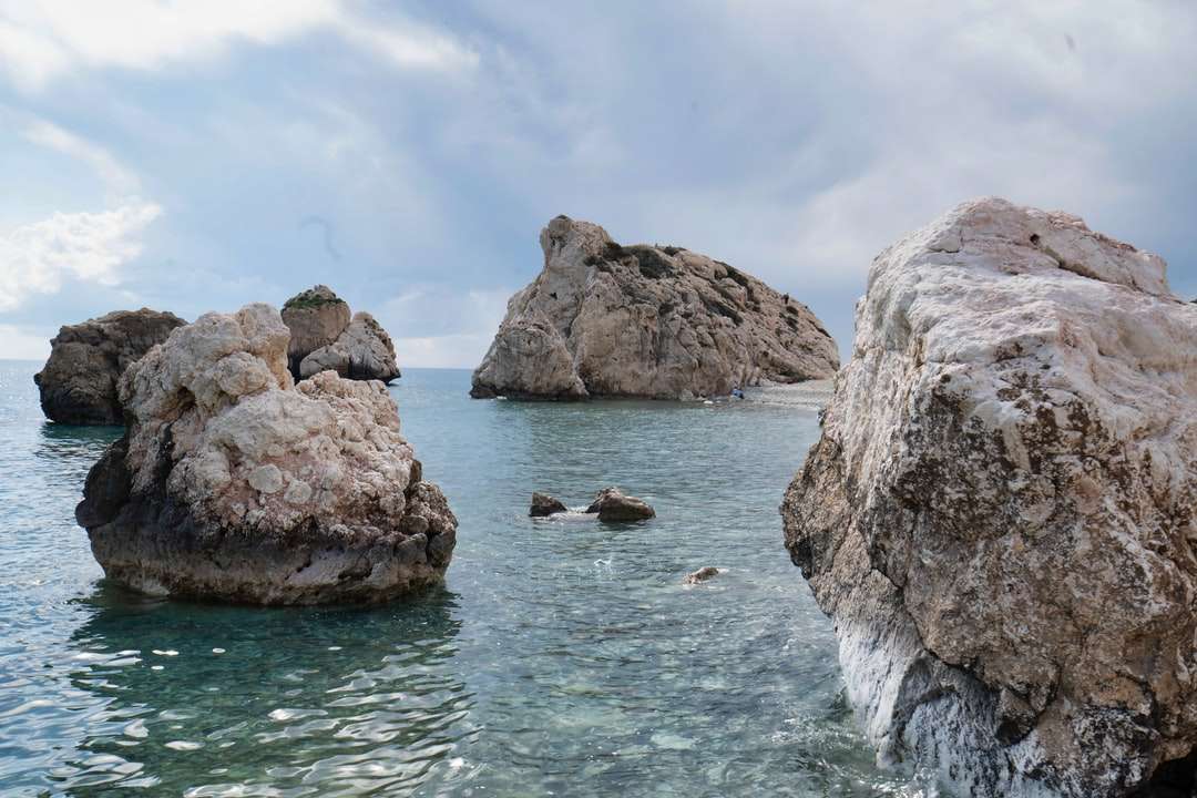 brązowa formacja skalna na morzu pod białymi chmurami puzzle online