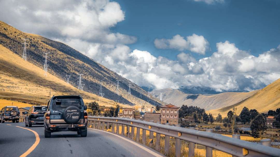 czarny suv na drodze w pobliżu góry pod błękitnym niebem puzzle online