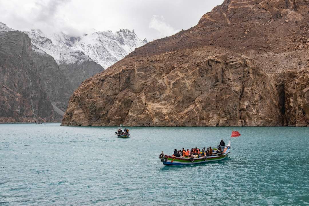ludzie jadący łodzią po morzu w pobliżu góry w ciągu dnia puzzle online