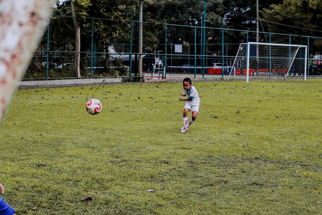 2 chłopców grających w piłkę nożną na zielonej trawie w ciągu dnia puzzle online