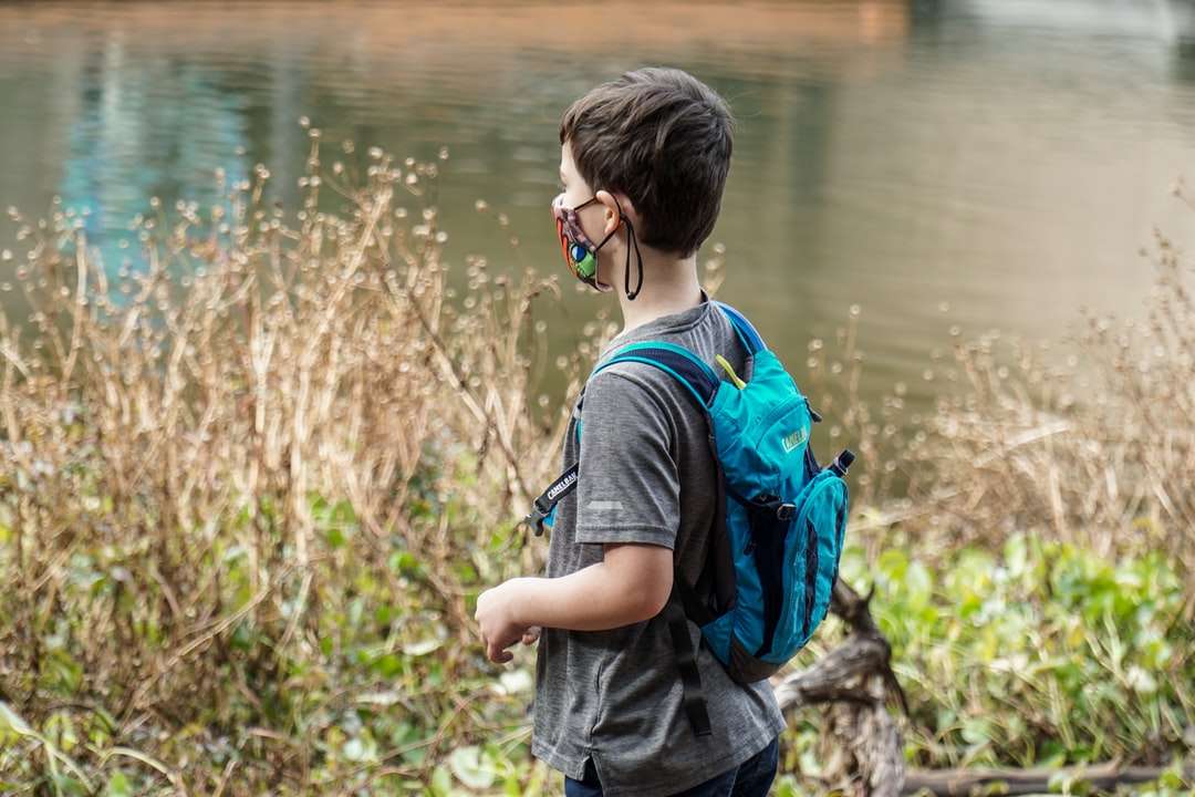 chłopiec w niebiesko-czarnym plecaku stojącym w pobliżu zbiornika wodnego puzzle online