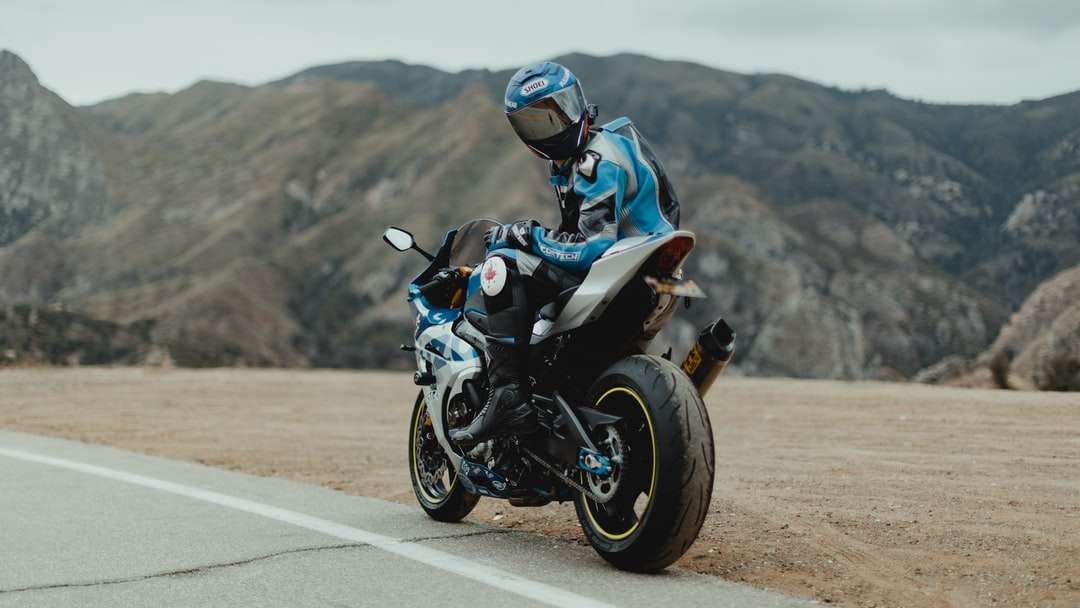 mężczyzna w niebiesko-białej kurtce na czarnym motocyklu puzzle online