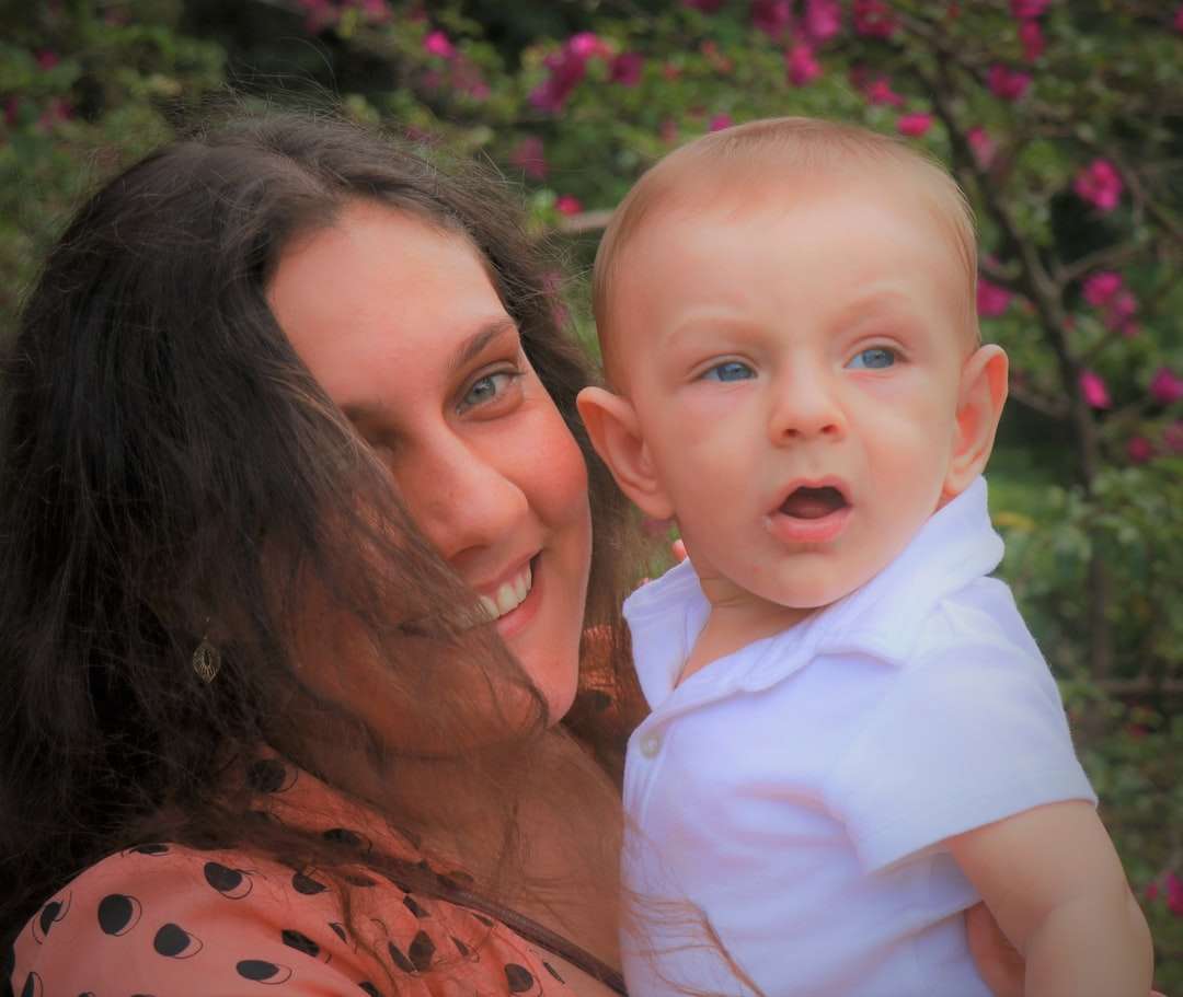 kobieta w pomarańczowo-czarnej koszuli niosąca dziecko w białej koszuli puzzle online