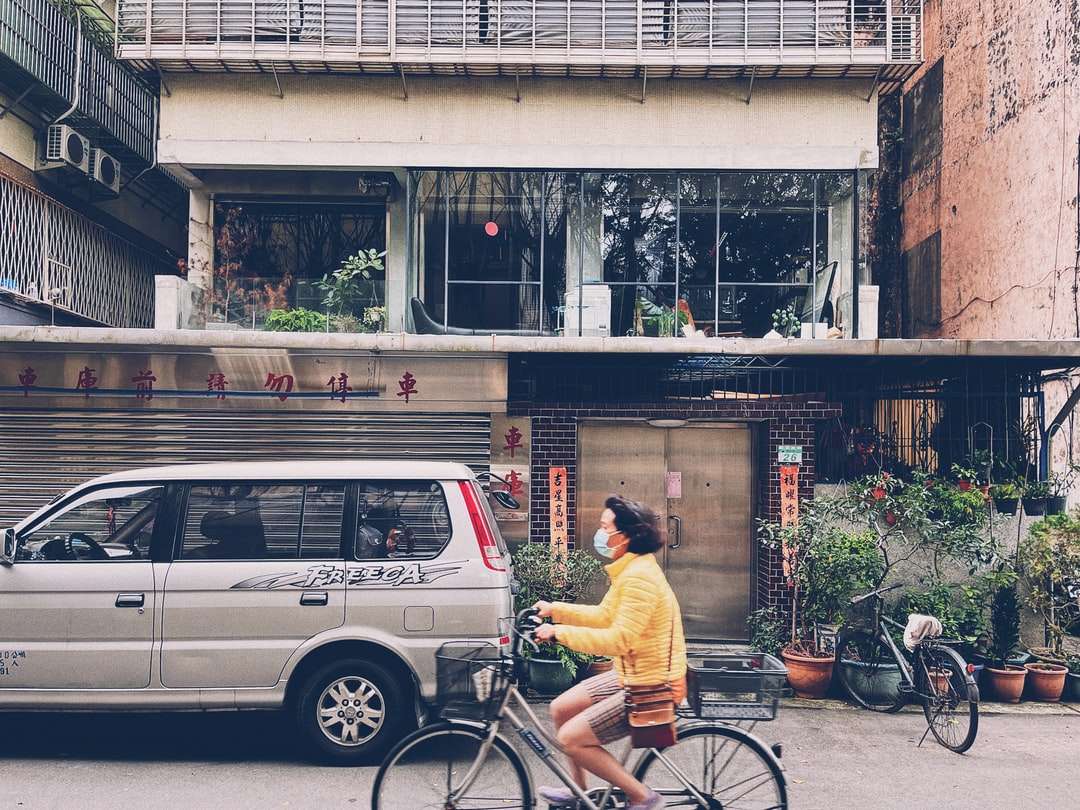 mężczyzna w żółtej koszuli, jazda na rowerze w pobliżu czarnego samochodu puzzle online