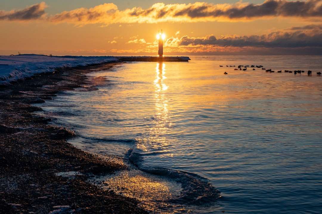 sylwetka latarni morskiej na plaży podczas zachodu słońca puzzle online