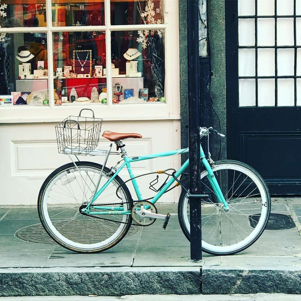 turkusowy rower miejski zaparkowany obok sklepu puzzle