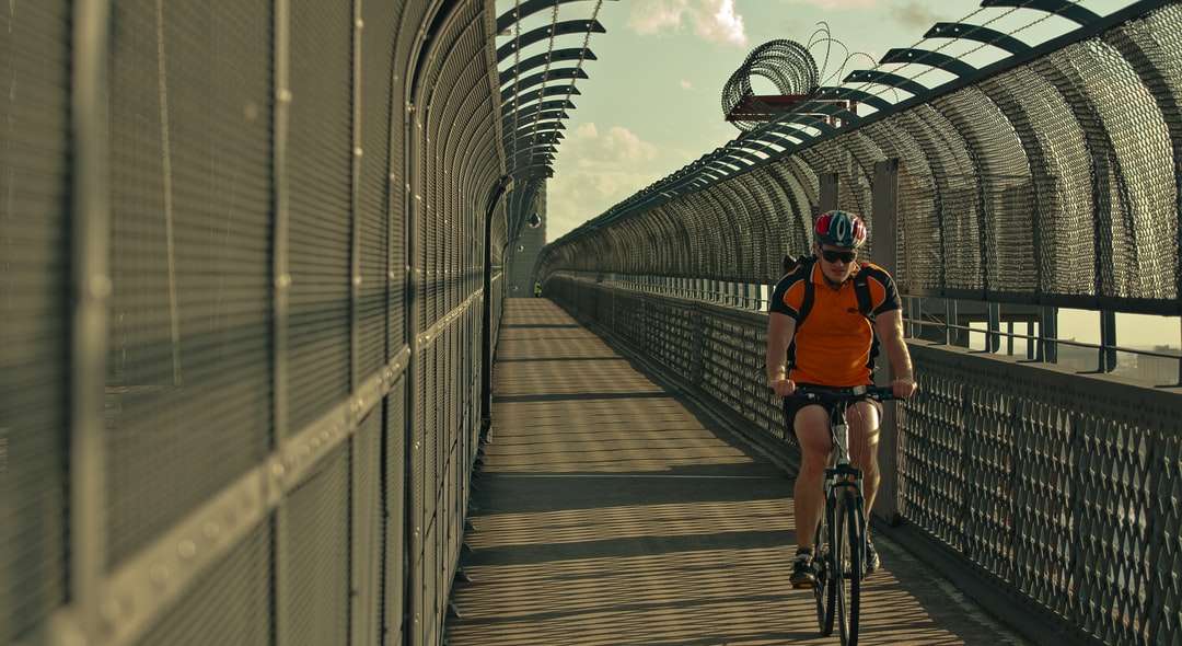 człowiek w pomarańczowej koszuli, jazda na rowerze na moście w ciągu dnia puzzle online