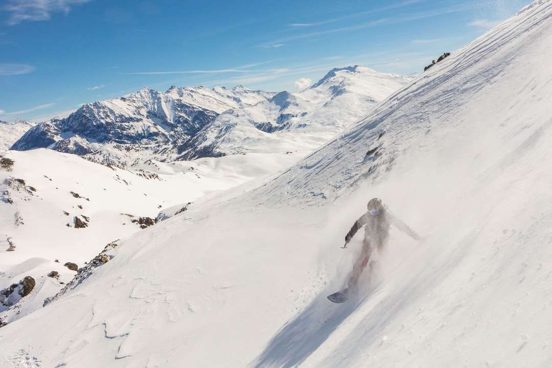 osoba spacerująca po zaśnieżonej górze w ciągu dnia puzzle online