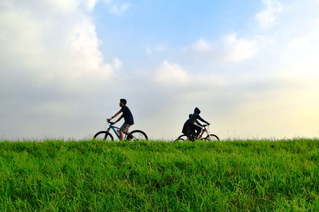 mężczyzna w czarnej koszuli, jazda na rowerze na polu zielonej trawie puzzle online