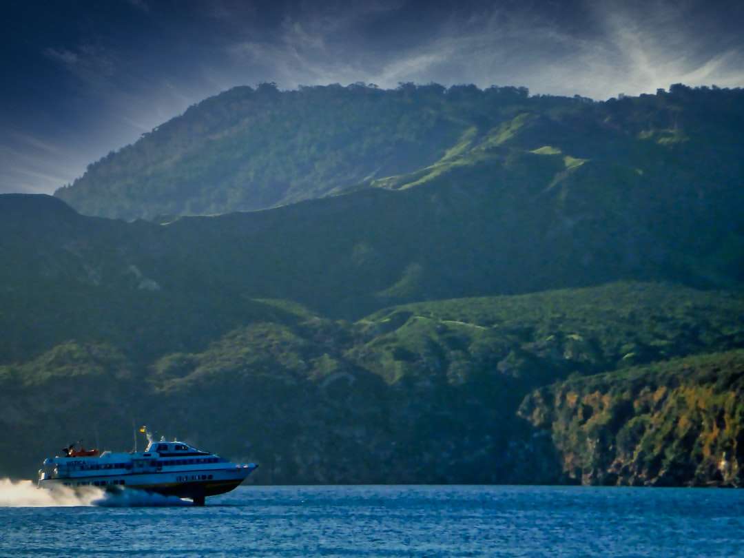 biało-czarna łódź na morzu w pobliżu góry w ciągu dnia puzzle online