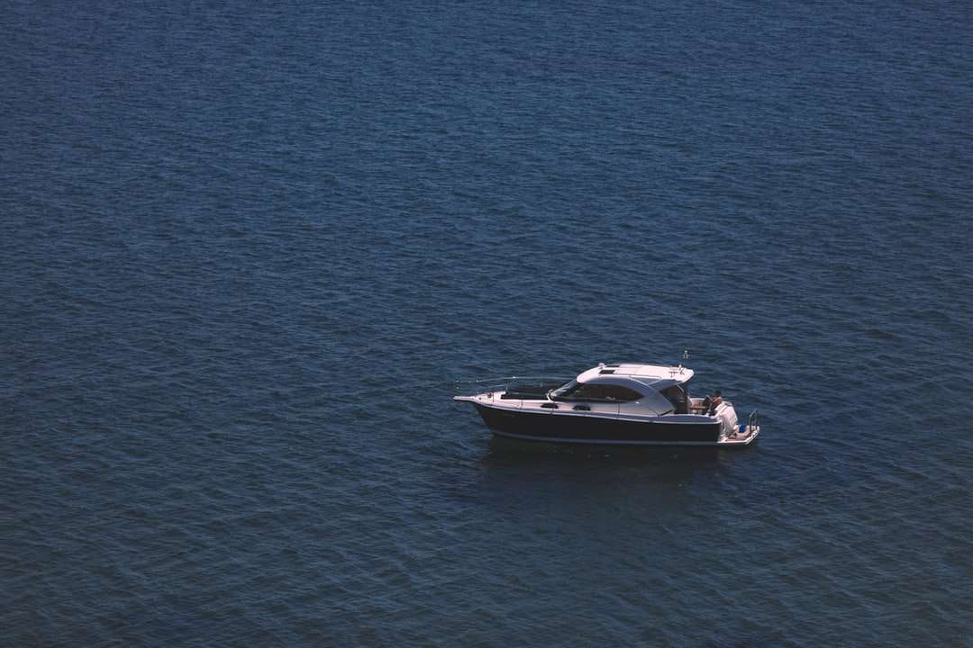 biało-czarna łódź motorowa na błękitnym morzu w ciągu dnia puzzle online