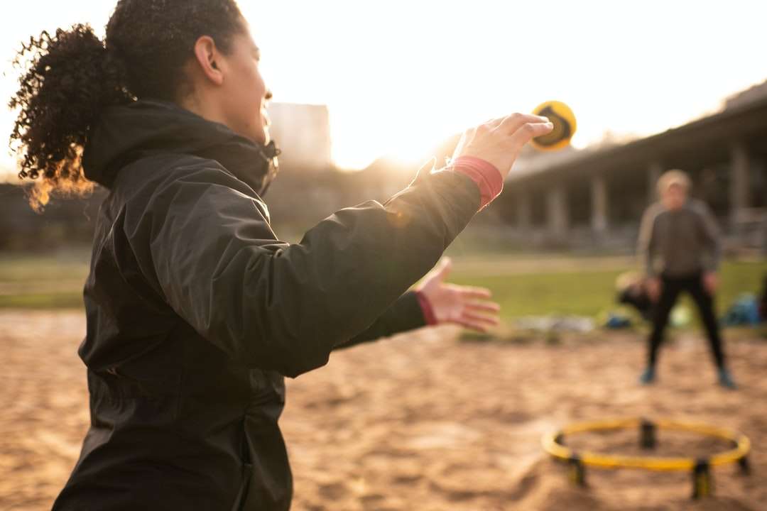 mężczyzna w czarnej kurtce trzymając żółtą piłkę w ciągu dnia puzzle online