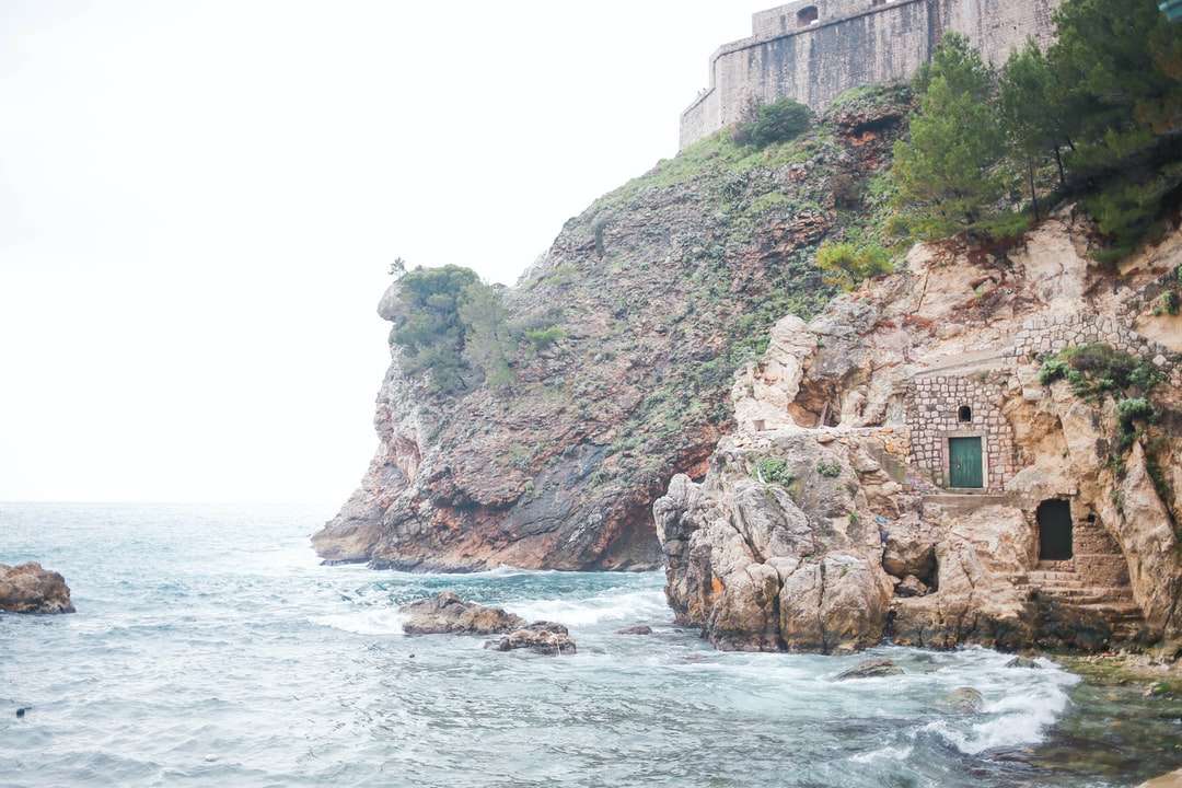 brązowy betonowy budynek na klifie nad morzem w ciągu dnia puzzle online