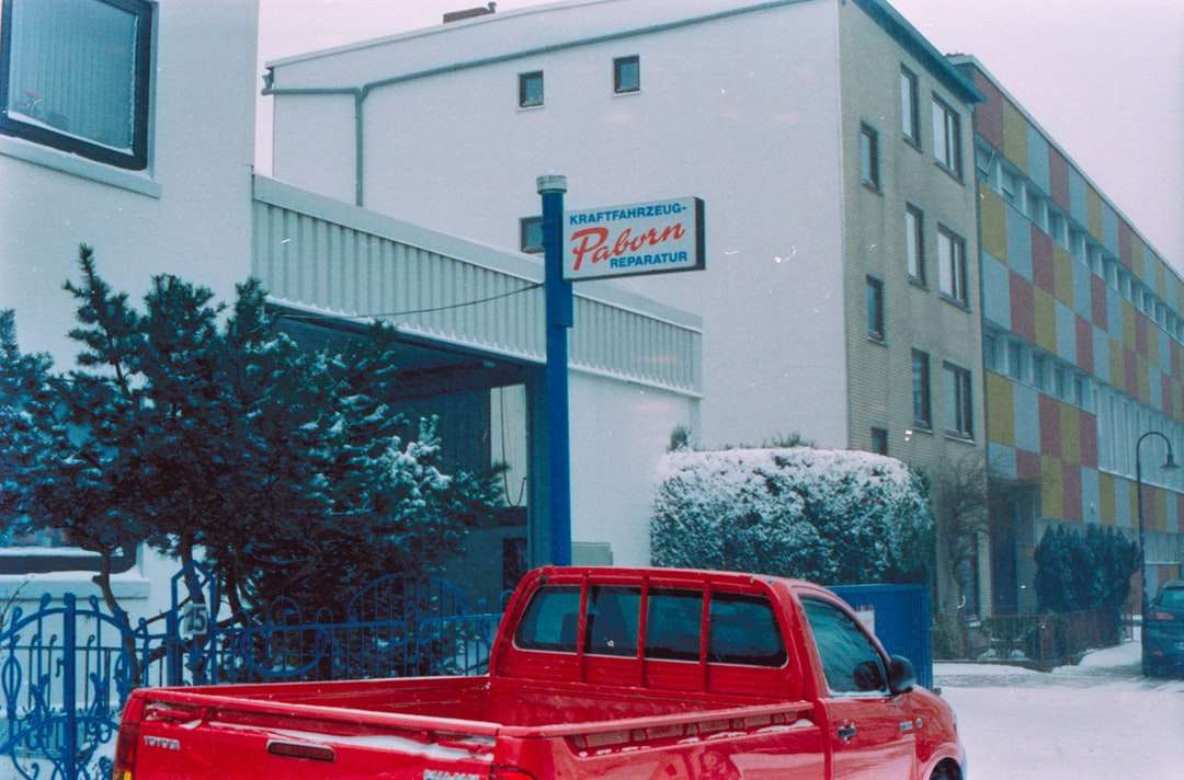 czerwona kabina pickupa zaparkowana w pobliżu białego budynku puzzle online
