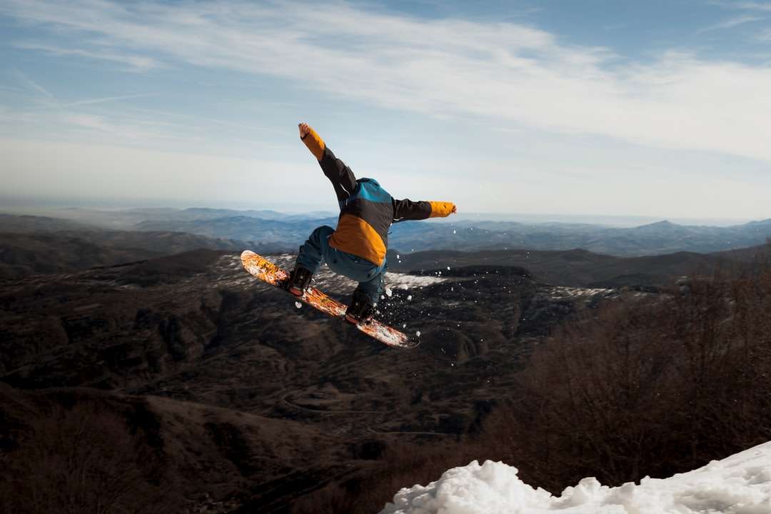 człowiek w niebieskiej kurtce i czarnych spodniach robi narty na śniegu puzzle online