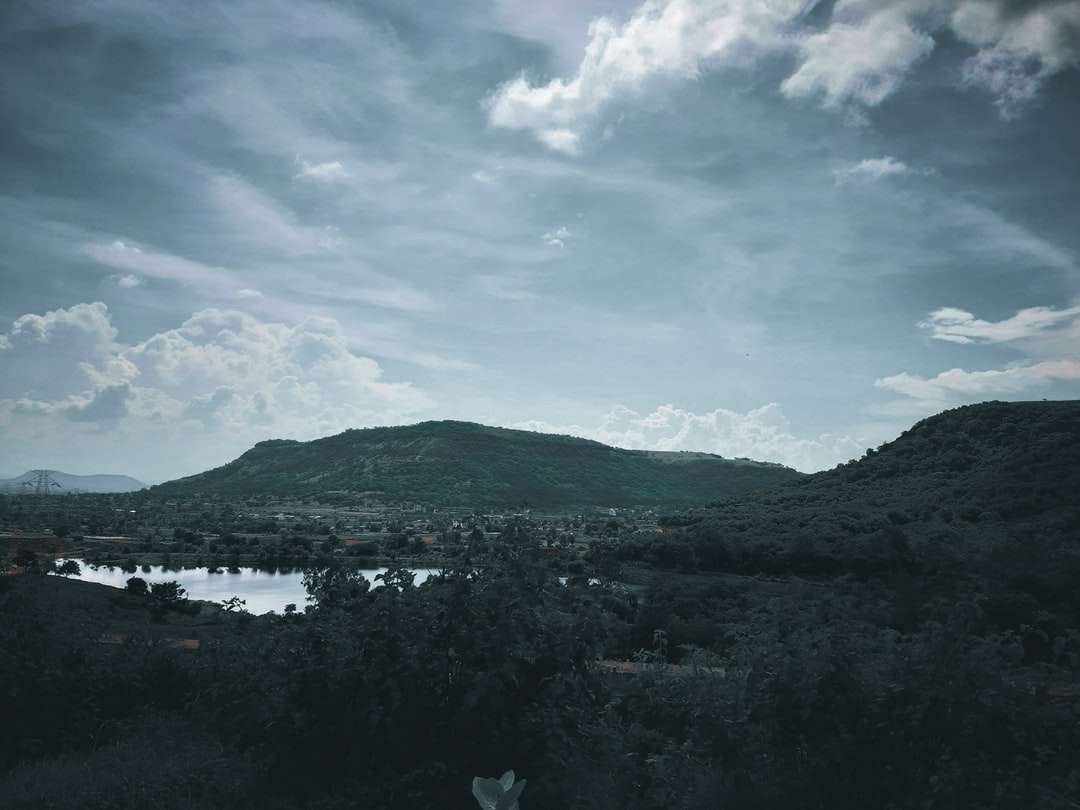 zielone góry w pobliżu zbiornika wodnego pod błękitnym niebem puzzle online