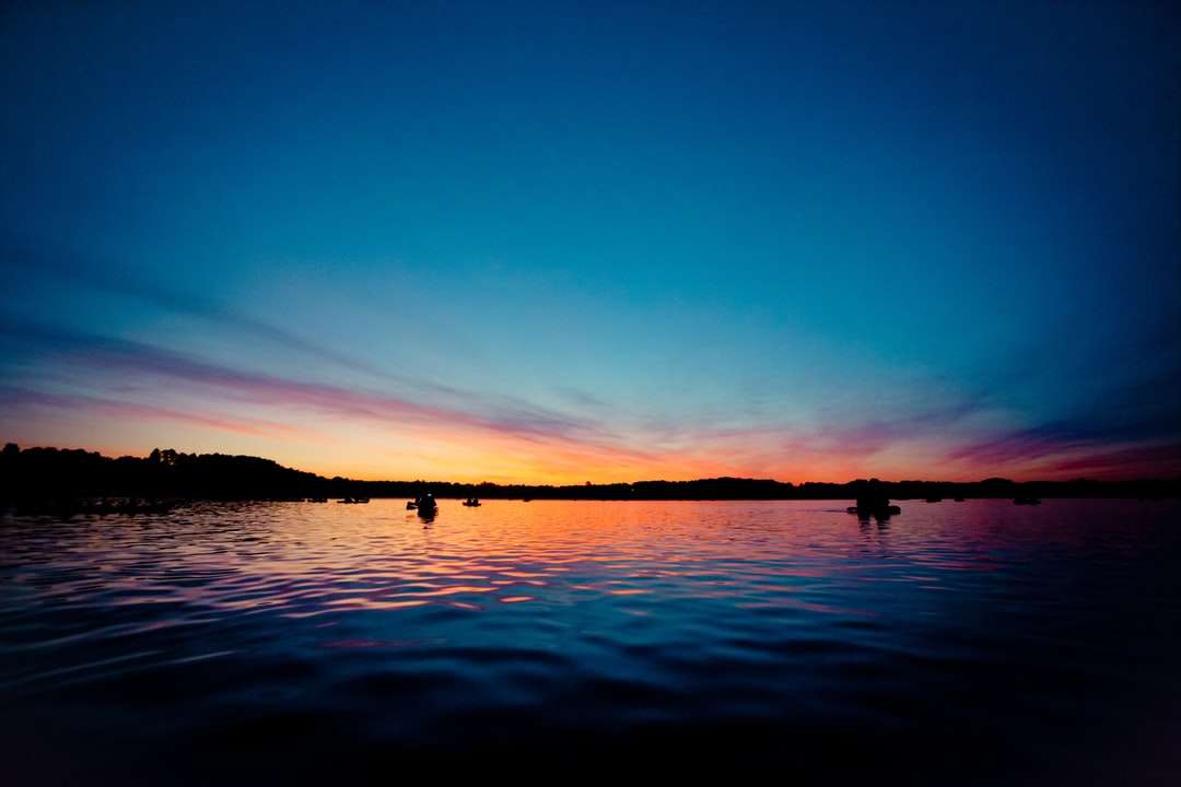 silueta de personas en el cuerpo de agua durante la puesta de sol rompecabezas