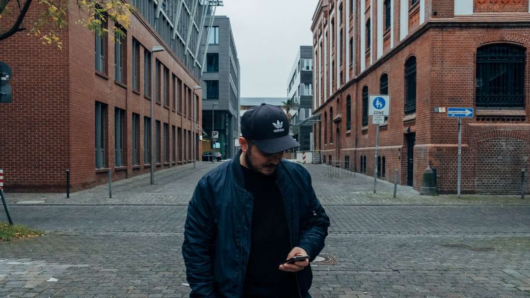 mężczyzna w czarnej kurtce i czarnej czapce stojącej na chodniku puzzle online