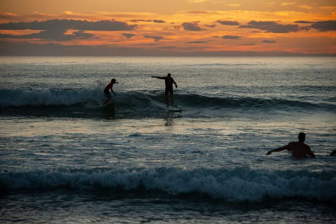 2 osoby surfuje na morskich falach podczas zachodu słońca puzzle online