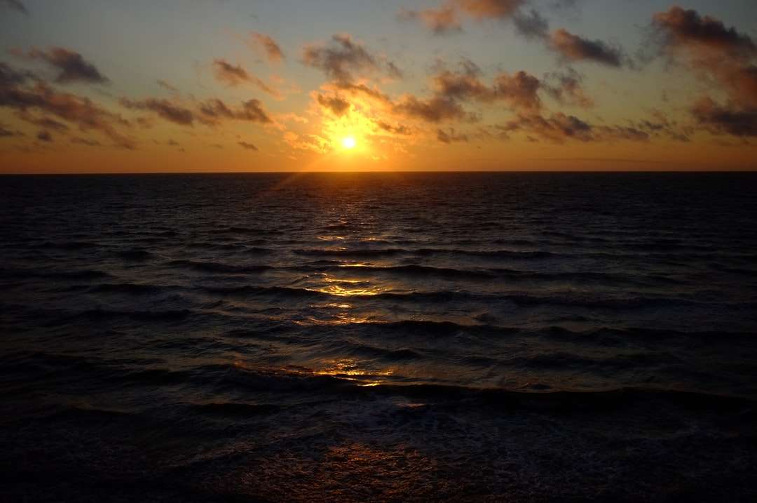 fale morskie rozbijające się o brzeg podczas zachodu słońca puzzle online