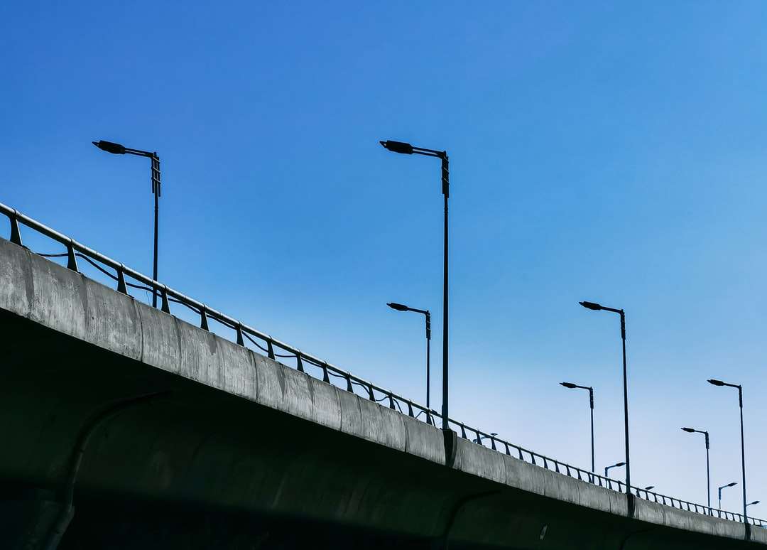czarny metalowy słupek na szarym betonowym moście pod błękitnym niebem puzzle online