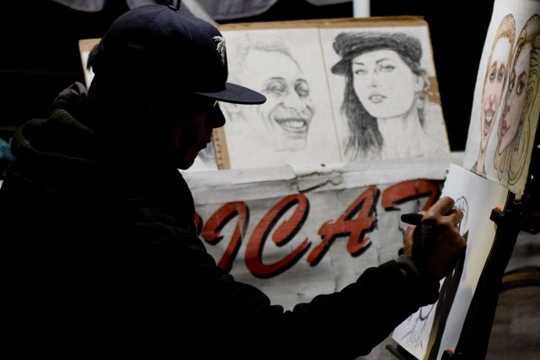 mężczyzna w czapce siedzi podczas robienia szkiców portretowych puzzle online