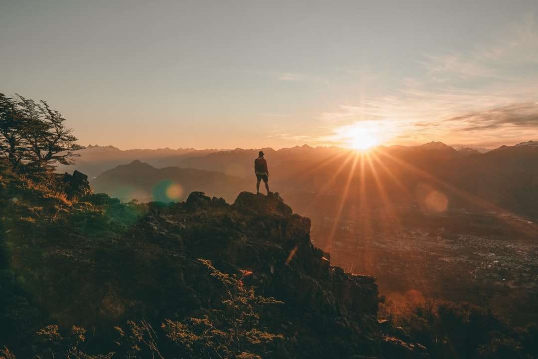 sylwetka osoby stojącej na skale podczas zachodu słońca puzzle online