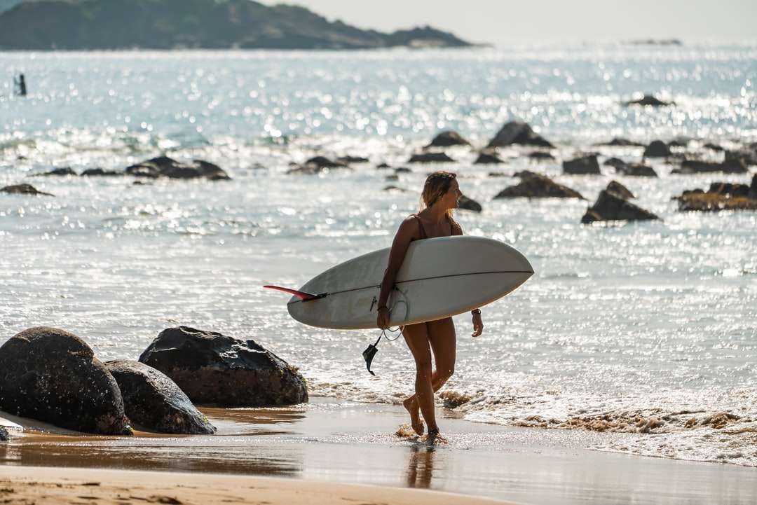 kobieta w czarnym bikini trzymając białą deskę surfingową puzzle online