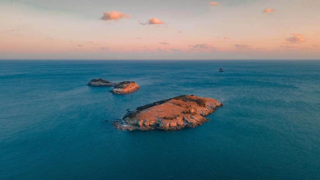 brązowa formacja skalna na błękitnym morzu pod błękitnym niebem puzzle online