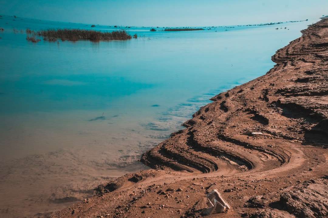brązowy piasek w pobliżu zbiornika wodnego w ciągu dnia puzzle online