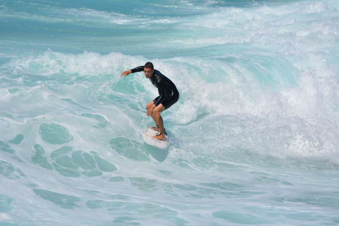 mężczyzna w czarnej koszuli i szortach, surfing na falach morskich puzzle online