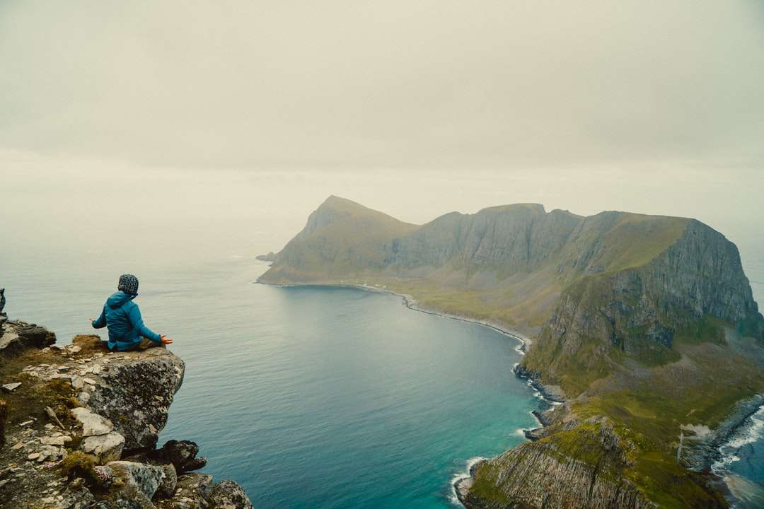 kobieta w niebieskiej kurtce siedzi na formacji skalnej w pobliżu ciała puzzle online