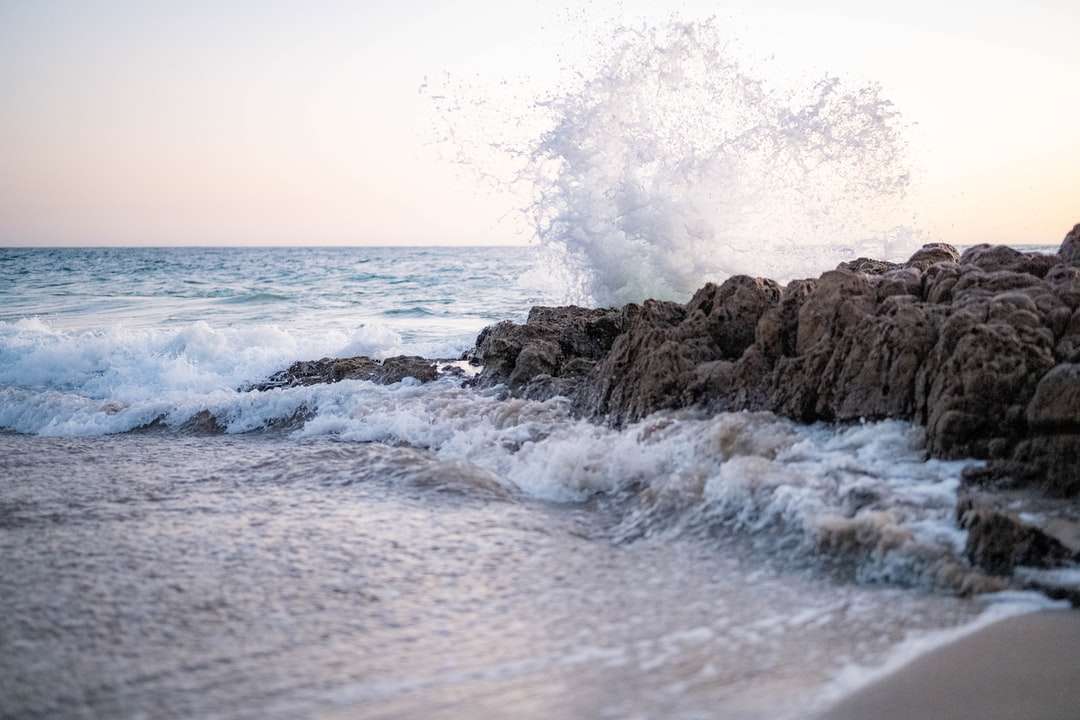 fale oceanu rozbijające się o brunatną formację skalną w ciągu dnia puzzle online