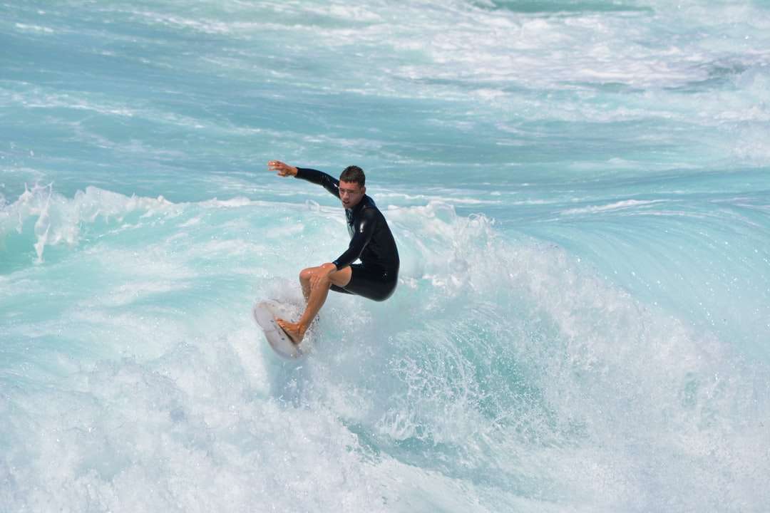 kobieta w czarnym kombinezonie surfing na morskich falach w ciągu dnia puzzle online