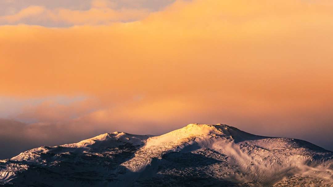 pokryte śniegiem góry pod pomarańczowym niebem puzzle online