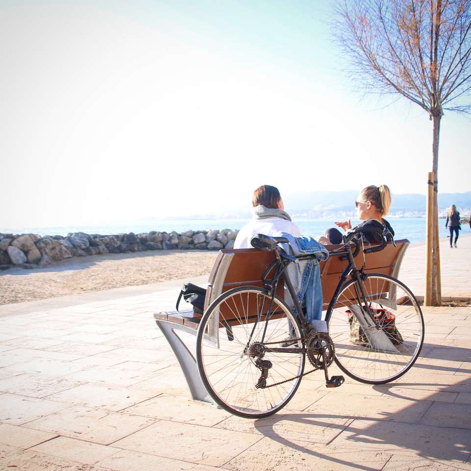 2 osoby siedzące na ławce z oparciem na rowerze puzzle online
