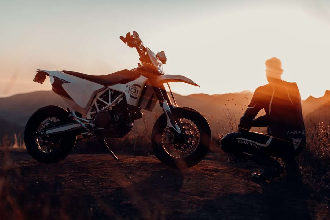 mężczyzna w czarnej kurtce siedzi na motocyklu podczas zachodu słońca puzzle online