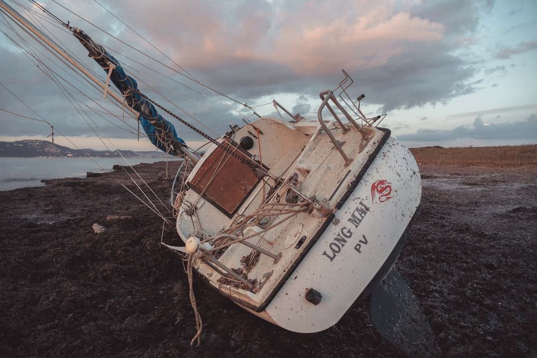 biało-brązowa łódź rybacka na brzegu morza w ciągu dnia puzzle online
