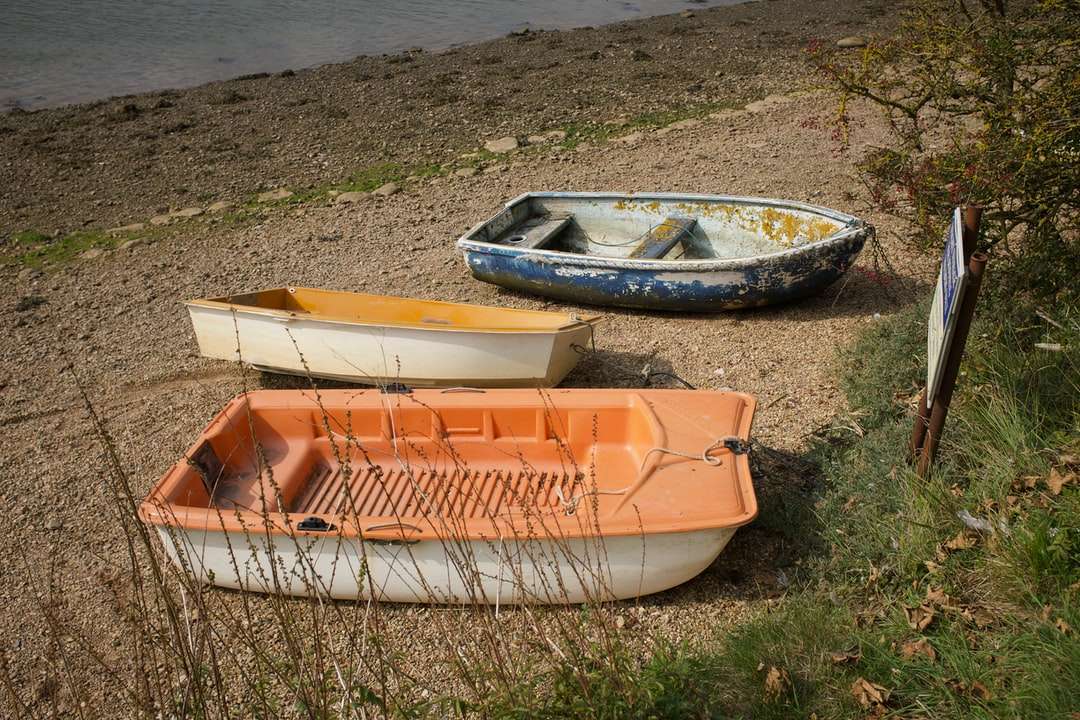 pomarańczowo-biała łódź na zielonej trawie w ciągu dnia puzzle online